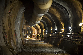 Image down the tunnel rounding a corner with lights along the way 
