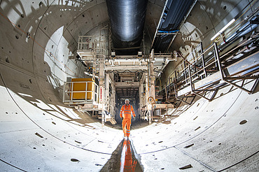 Person walking through a tunnel lined with concrete segments