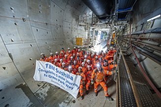 Gathering of people in a tunnel holding a sign saying 'TBM Sushila Completes 5 Mile Journey to Green Park Way'