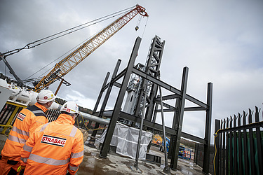Two people on a construction site watching a headhouse being constructed