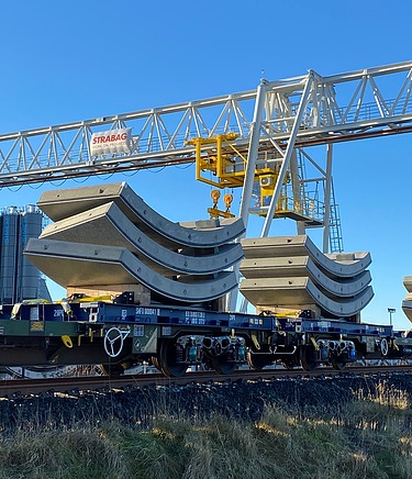Tunnel segments loaded onto train carriages with the gantry in the background