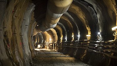 Image down the tunnel rounding a corner with lights along the way 