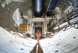 Person walking through a tunnel lined with concrete segments