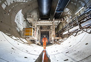 Person walking through a tunnel lined with concrete segments