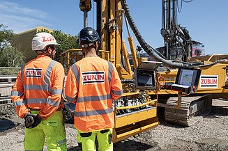 Two employees on site with a jet grouting machine in the background