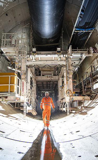 Person walking through a tunnel lined with concrete segments