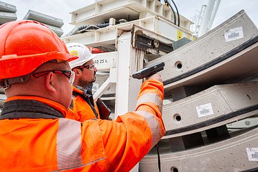 Two people on site scanning a barcode on a concrete tunnel segment