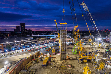 Ground engineering construction site in the UK with cranes installing deep foundations at dusk, illustrating STRABAG UK’s acquisition of Van Elle to strengthen geotechnical and civil engineering capabilities